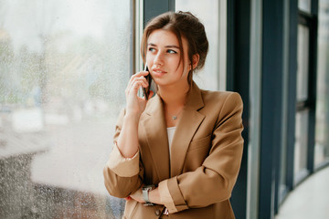 portrait of a young business woman. Smiling woman in casuals standing in office. Businesswoman with mobile phone in hand. 
young woman working in the office. talking on the phone. 