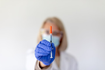 Medical professional doctor or nurse holding a vaccine in a syringe needle