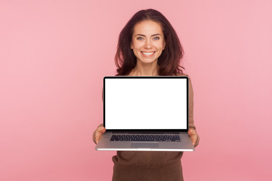 Portrait of beautiful woman holding laptop with white screen copy space, mock up display for internet advertising, online service, website promotion. indoor studio shot isolated on pink background