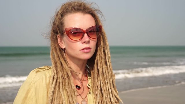 Portrait of a young hippie woman on a background of the sea. Hippie girl with dreadlocks