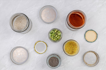 Home kitchen concept with top view of groceries in the jars. Spices and groceries in jars on the grey marble kitchen table