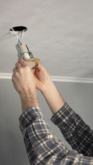 Installing spot light, hand inserts the lamp into the ceiling, close-up.