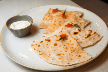 Yantyk with salmon, red caviar, served with sour cream sauce.