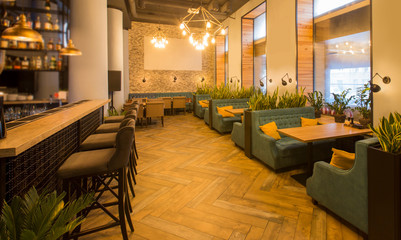 Modern restaurant interior with tables and sofas, bar counter