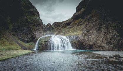 View from flying drone of Stjornarfoss waterfall. with person Impressive summer sunrise in Iceland, Europe. Beauty of nature concept background. Travel to Iceland..