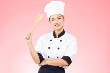 Naklejka premium Beautiful Asian chef woman smile and holding wooden Spatula isolated on pink background,Happiness and Cheerful Professional chef Concept