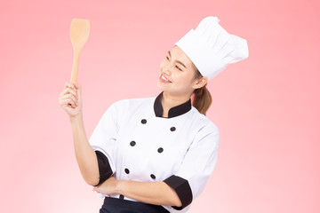 Naklejka premium Beautiful Asian chef woman smile and holding wooden Spatula isolated on pink background,Happiness and Cheerful Professional chef Concept