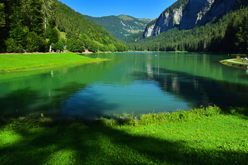 Fototapeta na wymiar Lake of Montriond, natural lake in Portes du Soleil, Haute -Savoie region, France, an attraction for many tourists, with swimming area, fishing, canoeing.