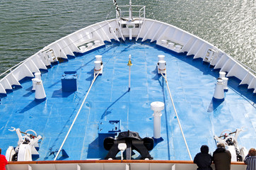 Panoramic view over bow of cruiseship or cruise ship liner with railing and wooden deck onto...
