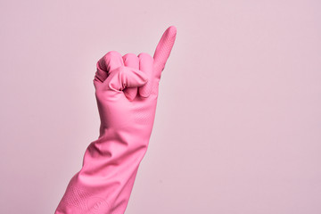 Hand of caucasian young man with cleaning glove over isolated pink background showing little finger...