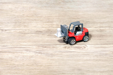 Toy forklift on wood background.