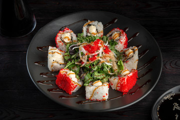set sushi rolls on a round plate on a dark wooden background