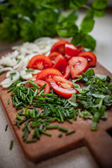 Fresh vegetables and herbs chopped for salad on wooden desk tomato onion chives basil