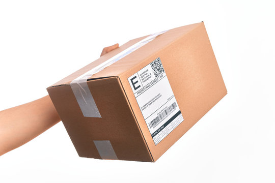 Hand of caucasian young man holding cardboard package showing label with codebar over isolated white background