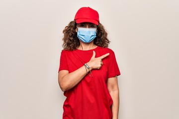 Middle age delivery woman wearing red cap and coronavirus protection mask smiling cheerful pointing with hand and finger up to the side