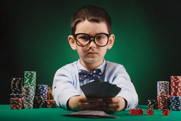 Little kid boy playing poker in a casino.