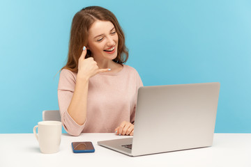 Call me! Happy pretty woman doing talking on telephone gesture and looking at laptop screen,...