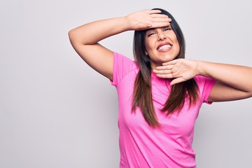 Fototapeta premium Young beautiful brunette woman wearing casual pink t-shirt standing over white background Smiling cheerful playing peek a boo with hands showing face. Surprised and exited