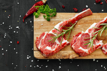 Racks of lamb ready for cooking on dark background, close up