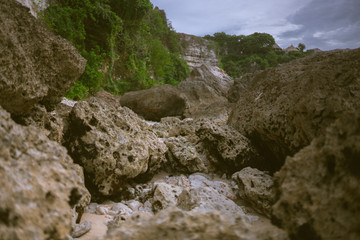 Beautiful deserted beach on the island of Bali at sunset. Rocks and nature. Plants and houses on the coast. Tropical paradise. Stones and white sand on the ocean