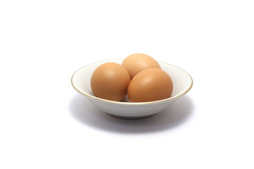 A group of chicken eggs on a small plate isolated on white background