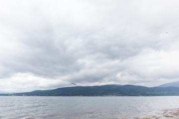A mystical fjord in Norway with mountains and fog hanging over the water in a beautiful monochrome blue color.