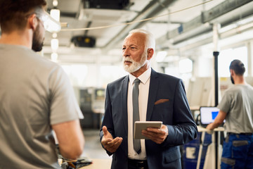 Senior company manager talking with a worker in industrial facility.