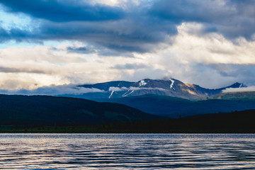 Spectacular view of a mountain range in clouds near a lake in Ulagansky district of the Altai Republic, Russia