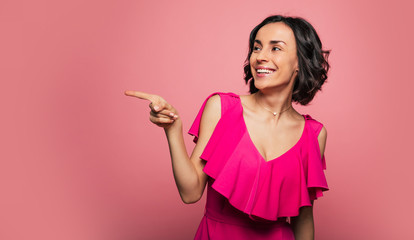 That is my choice. Cheerful young woman in a fuchsia dress is looking and pointing to the left,...