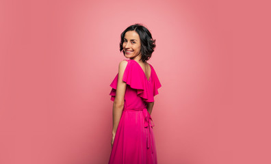 New dress. Portrait of a wonderful happy girl in a long magenta dress, who is looking in the camera over her shoulder with enigmatic smile.