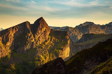 Fototapeta na wymiar Sunset across a rugged mountain range in the Lofoten region of Norway during summer. Nobody visible in the photo.