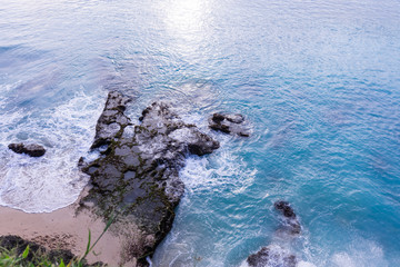 Beautiful deserted beach on the island of Bali at sunset. Rocks and nature. Plants and houses on the coast. Tropical paradise. Stones and white sand on the ocean