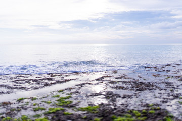 Beautiful deserted beach on the island of Bali at sunset. Rocks and nature. Plants and houses on the coast. Tropical paradise. Stones and white sand on the ocean