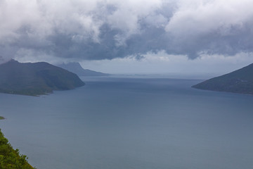 Norwegian fjord and mountains surrounded by clouds, ideal fjord reflection in clear water. selective focus.