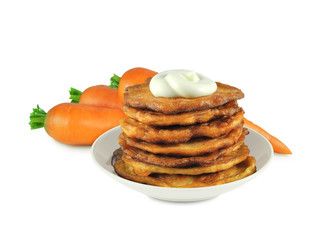 Stack of crunchy carrot pancakes with sour cream on top on saucer and fresh carrots behind isolated on white background. Vegetable snack.          