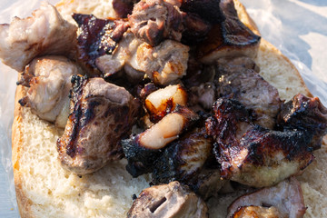 Skewers of meat close-up on pita bread. Tasty pieces of grilled meat. Meat cooked over an open fire. Outdoor picnic concept
