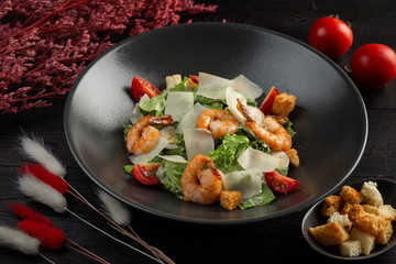 caesar salad with shrimp on a dark wooden background