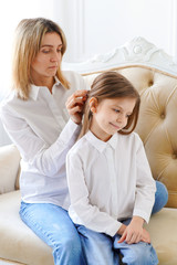 Mom straightens her daughter's hair. Parents and children. Family values and relationships of aunts...
