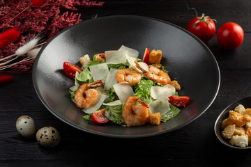 caesar salad with shrimp on a dark wooden background