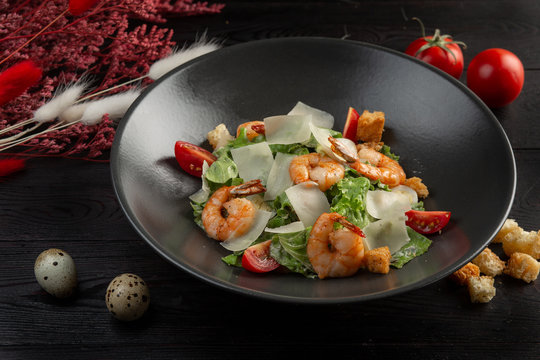 caesar salad with shrimp on a dark wooden background