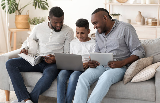 African Male Family With Laptop, Digital Tablet And Magazine At Home