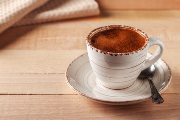 Coffee cup and saucer on a wooden table. Light background