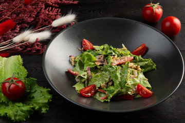 salad with tomatoes and leafy greens on a dark wooden background