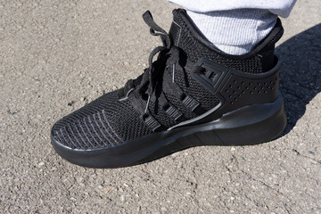 dark running shoes on the asphalt in the sun