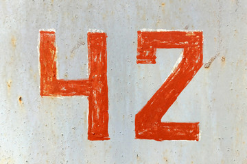 Number 42 red stencil digit painted on weathered gray metal surface