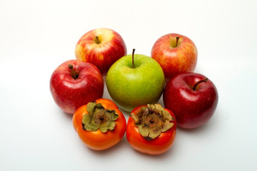Five apples and two persimmons on a light background