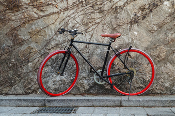 A red bicycle is parked next to a stone wall