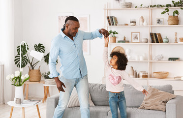 Fototapeta premium Stay home family fun. Cheerful older man with his granddaughter dancing in living room