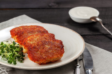 Potato pancakes with sour cream and dill on a wooden table