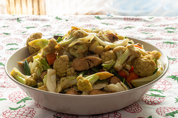 stir fry salad, asian style cooked. Salad with cauliflower, chicken, onion, broccoli and lettuce served on a plate